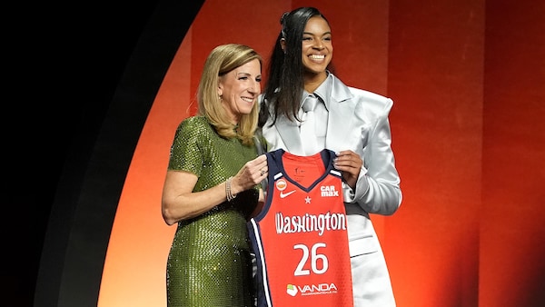 Deux femmes présentent une camisole de basketball.