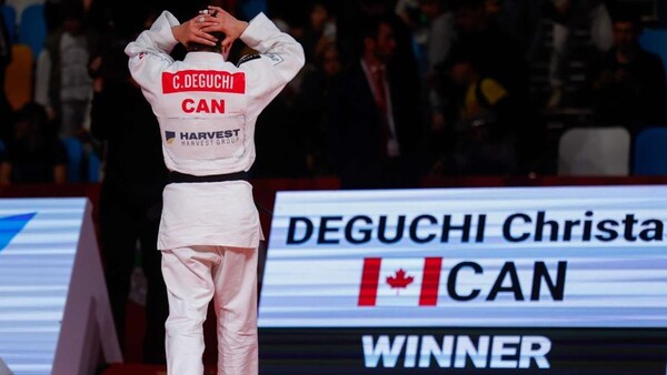 Une athlète de judo, de dos, quitte la surface de combat les mains derrière la tête. 