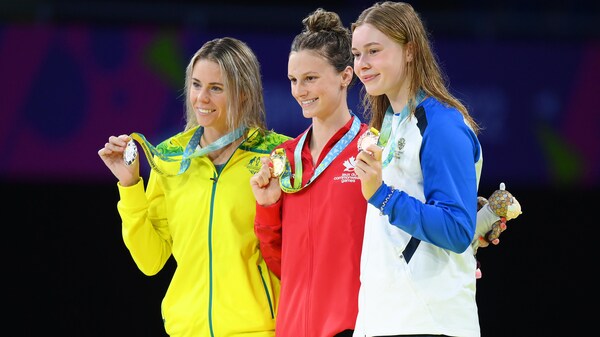 Les trois nageuses posent avec leurs médailles sur le podium.