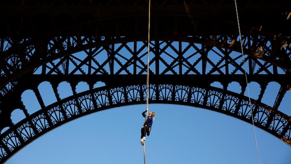 Suspendue à la tour Eiffel, elle s'accroche à une corde et regarde vers le haut.