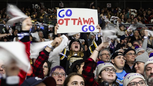 Une jeune fille avec une pancarte «Go Ottawa Go» pendant un match de hockey féminin.
