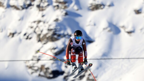 La skieuse saute devant des montagnes enneigées.