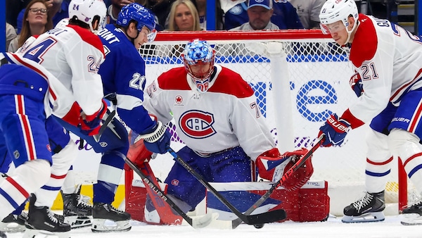 Des joueurs de deux équipes de hockey se disputent la rondelle devant un gardien. 
