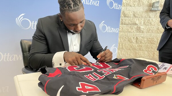Un joueur de football signe un autographe sur un chandail.