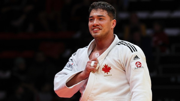 Un judoka canadien tient son judogi de sa main droite pour montrer sa feuille d'érable.