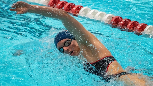 Une nageuse fait du crawl, et a le bras gauche hors de l'eau, dans une piscine pendant une compétition.