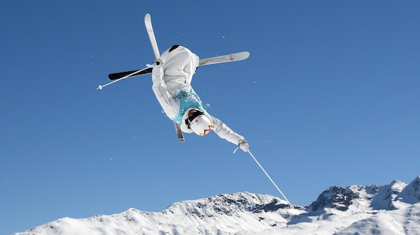 Mikaël Kingsbury croise les skis, tête en bas, lors d'une figure de ski acrobatique.