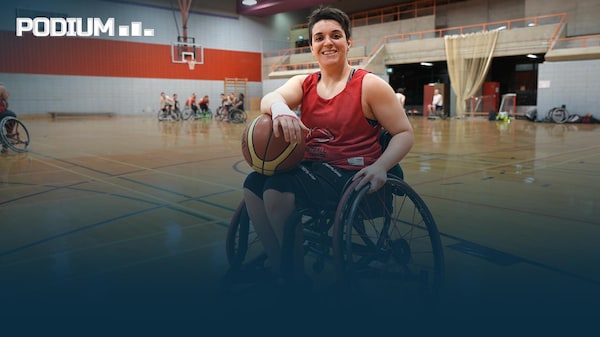 Une joueuse de basketball en fauteuil roulant sourit au milieu d'un gymnase