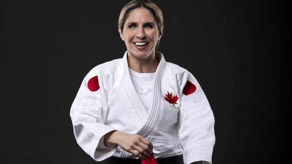 L'athlète de parajudo Priscilla Gagné est debout, en judogi, et tient un drapeau canadien dans ses mains. 