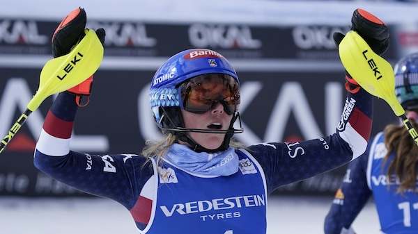 Une skieuse réagit en levant les bras après sa victoire.