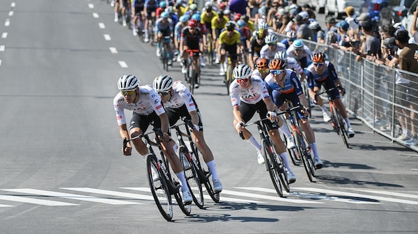 Trois cyclistes de l'équipe UAE roulent en avant du peloton dans les rues de Montréal. 