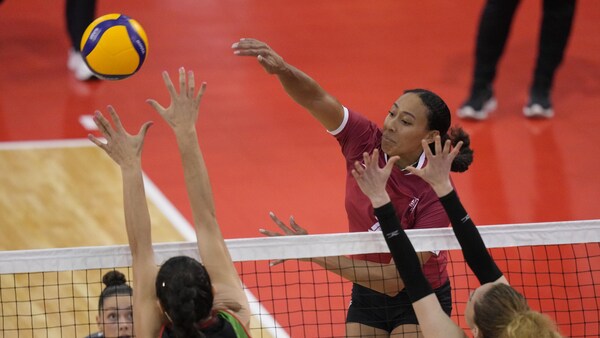 Une joueuse volleyball tente de bloquer le ballon au filet.