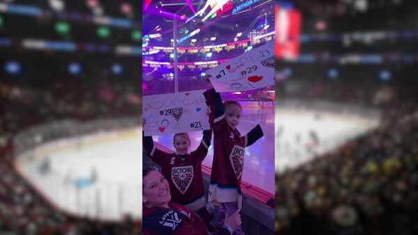 Deux jeunes partisanes de la Victoire montrent leur affiche devant la baie vitrée du Centre Bell.