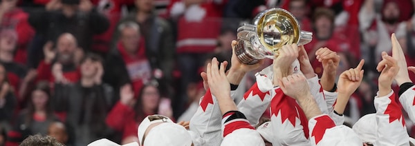 Des joueurs de hockey brandissent un trophée à bout de bras.