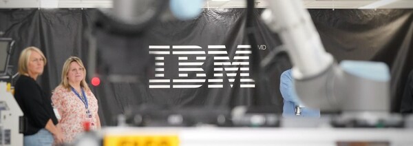 Le logo IBM apparaît sur une toile au fond d'une salle.