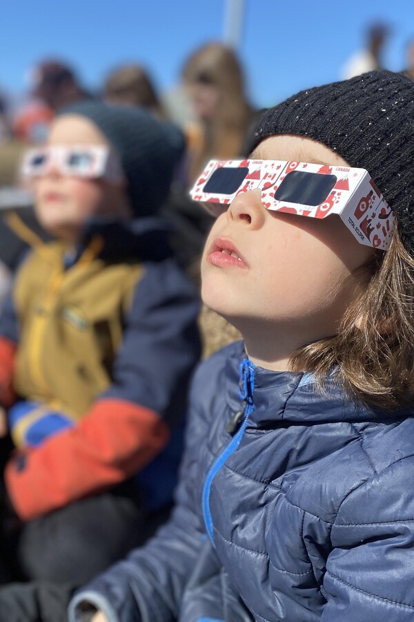 Un garçon regarde le ciel avec des lunettes de protection.