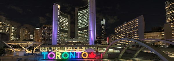 Vue nocturne sur ce grand ensemble architectural marqué par une enseigne lumineuse montrant le mot Toronto.