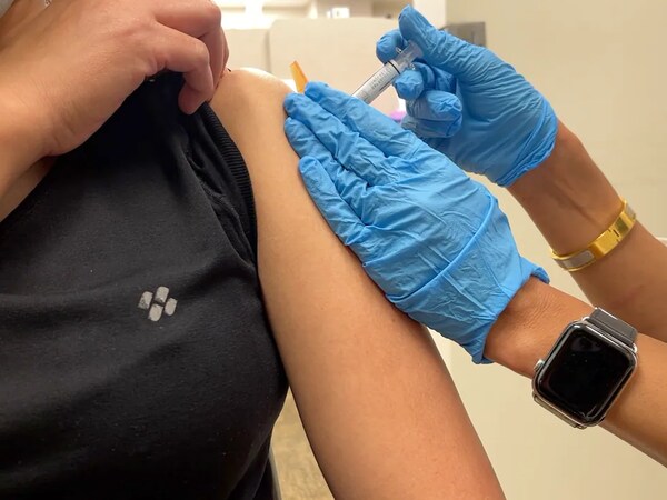Une personne reçoit une dose de vaccin dans l'épaule.