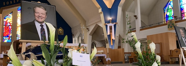 Une gerbe de fleurs se trouve devant la photo d'un homme dans une église.