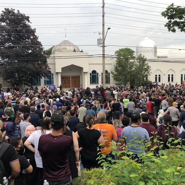 Un grand groupe de personnes rassemblées devant une mosquée.