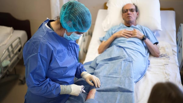 Une infirmière traite un patient allongé sur un lit d'hôpital.