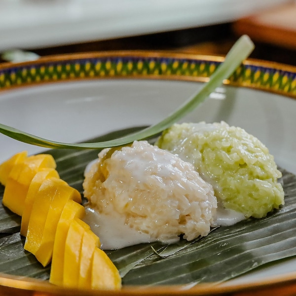Deux boules de riz sont disposées dans une assiette à côté d'une mangue tranchée.