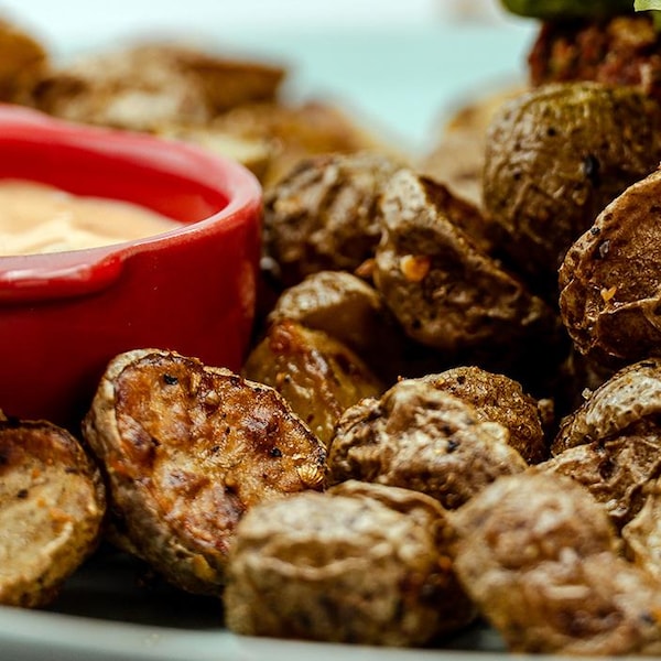 Une assiette de pommes de terre rôties aux épices à steak de Montréal, accompagnée d'une sauce Sauce McOrsini.
