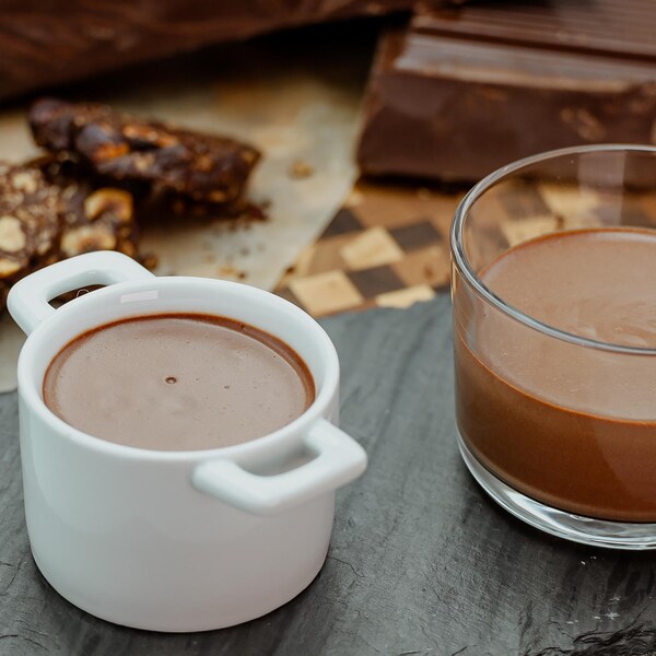 Deux petits pots de crème au chocolat servis sur une planche de service.