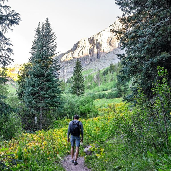 L'homme porte un sac à dos. Il se dirige vers une montagne.