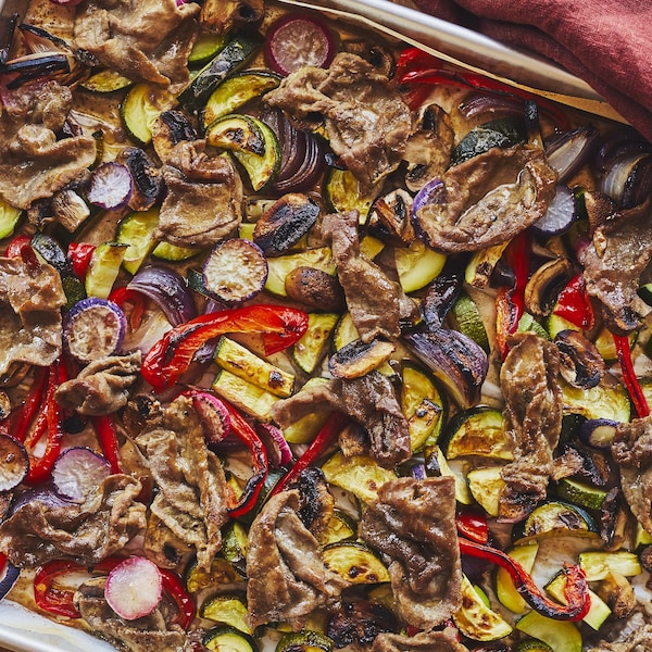 Une plaque remplie de légumes grillés et de tranches minces de bœuf.