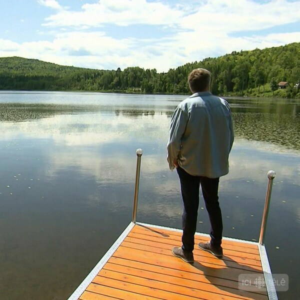 Réal Bossé se tient debout sur un quai et regarde au large d'un paisible lac.
