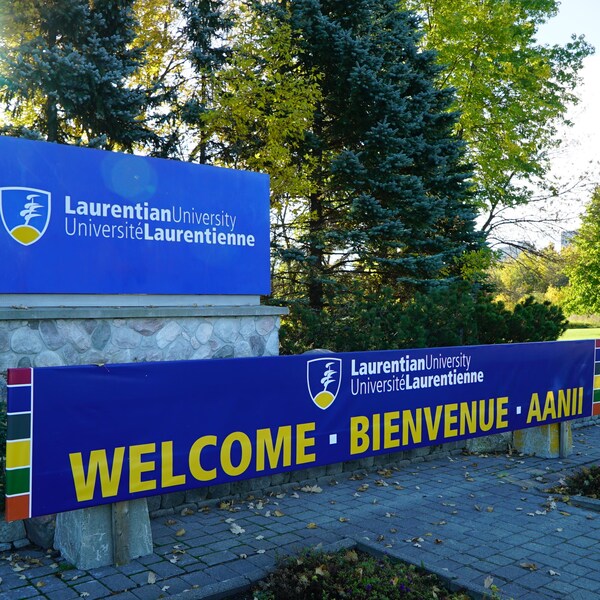 Affiche à l’entrée de l’Université Laurentienne de Sudbury où l’on voit le nom et le logo de l’établissement.