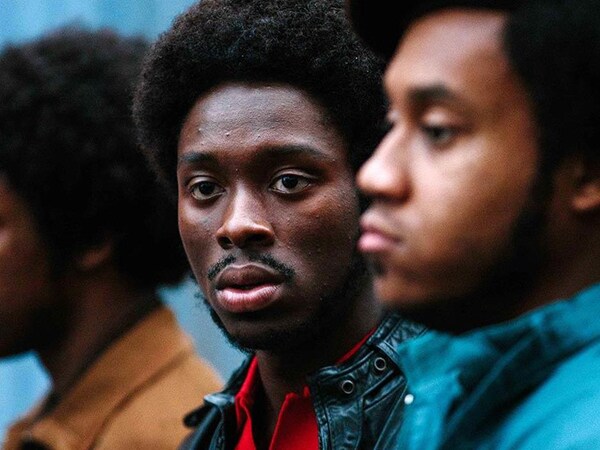 Trois jeunes hommes noirs, deux de profil et un regardant vers la gauche.