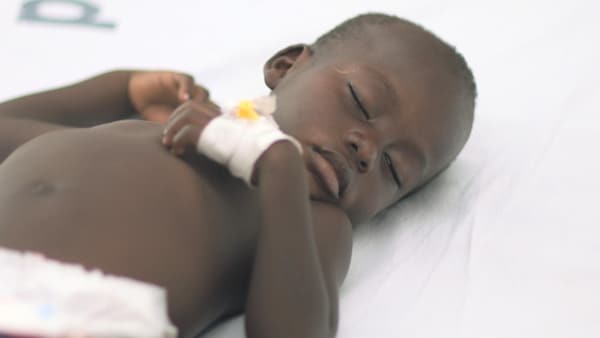Un enfant malade se repose sur un lit.