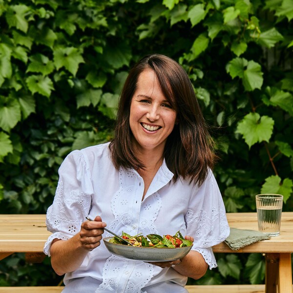 Geneviève O'Gleman est assise à une table de pique-nique et tient un bol rempli de laitue et de légumes frais.