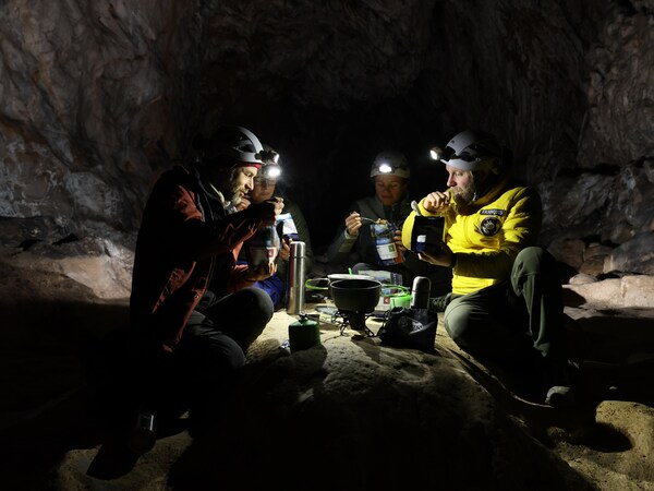 Quatre personnes mangent un repas dans la grotte.