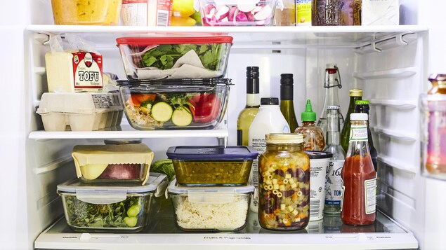 Sur l'étage du milieu d'un réfrigérateur, des ingrédients sont bien rangés et alignés. Les aliments solides sont placés à gauche et les aliments liquides sont placés à droite.