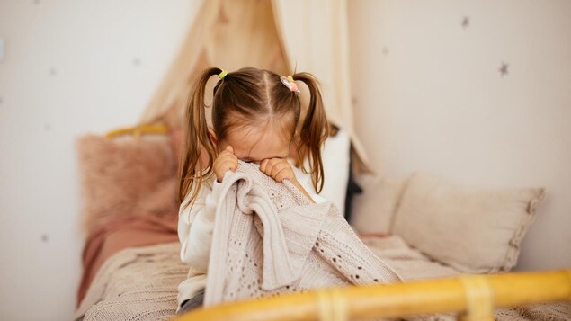 Une fille pleure dans son lit. 