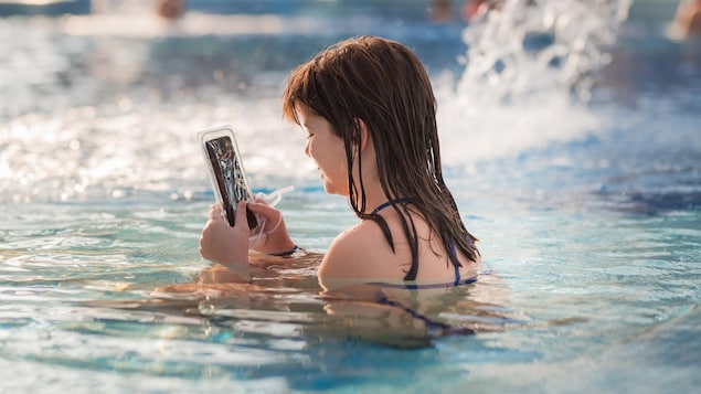 Une adolescente regarde lad   téléphone dans une piscine.