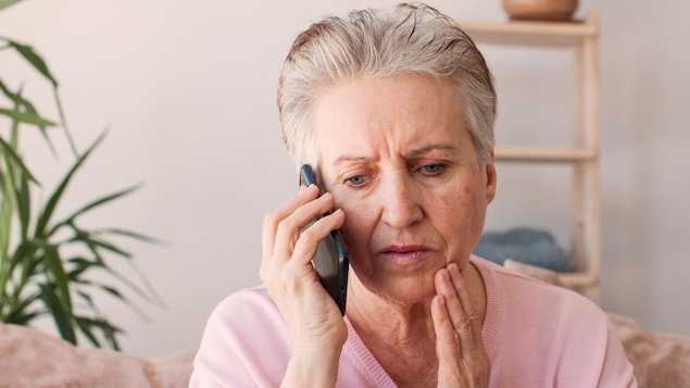 Une femme âgée avec un air stressé parle au téléphone.