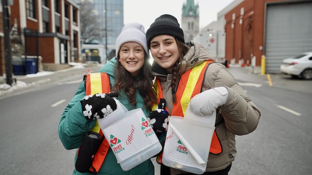 Deux jeunes qui sourient avec des cannes du Noël du pauvre dans les mains dans un barrage à Trois-Rivières.