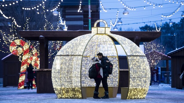 Un couple s'embrasse dans une grosse boule de Noël.
