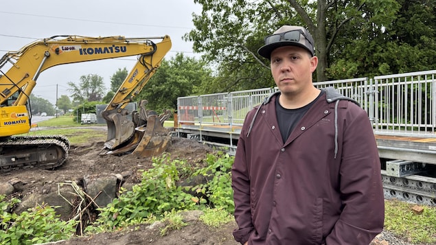 Il se tient devant le chantier.