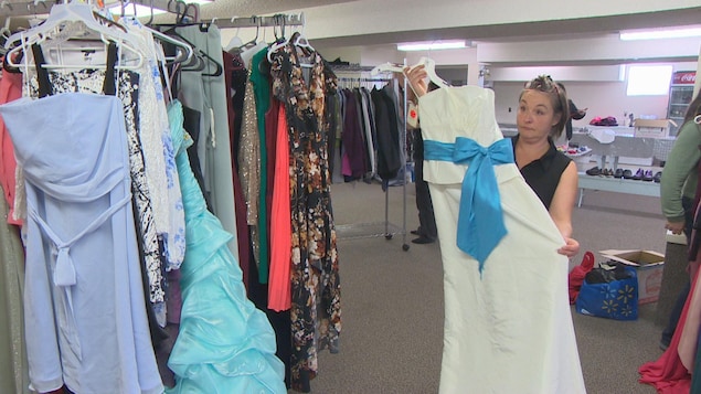 Une volontaire présente une des robes prêtes à être offerte aux élèves dans le sous-sol de l’église Dayspring Fellowship à Sainte-Anne.
