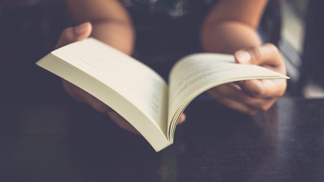 Gros plain sur les mains de la lectrice et sur le livre.