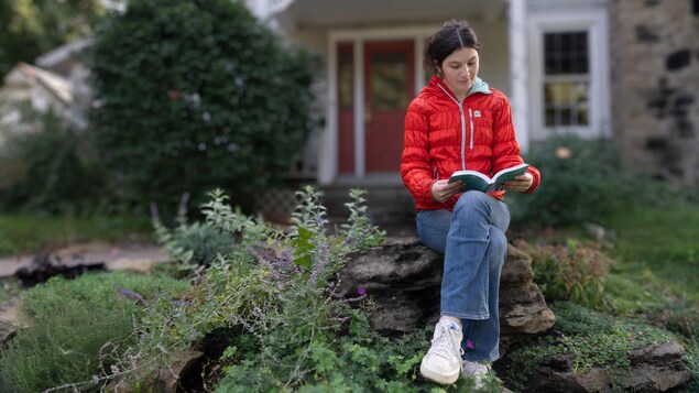 Une cégépienne en pleine lecture d'un livre devant sa maison familiale.
