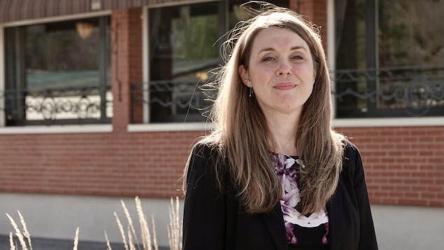 Gros plan de Kathleen Gélinas devant un édifice rouge.