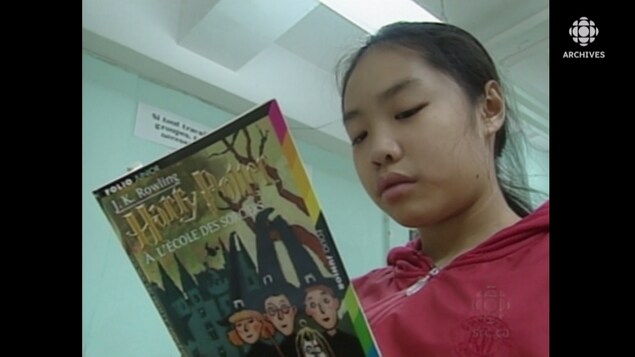 Une jeune fille lit le roman « Harry Potter à l'école des sorciers».