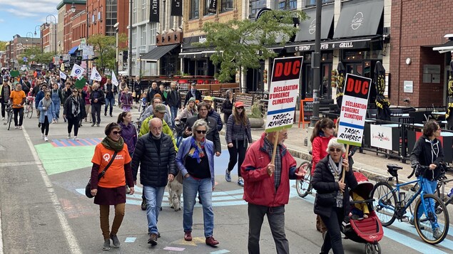 Des gens marchent sur la rue des Forges à Trois-Rivières avec des pancartes à la main.