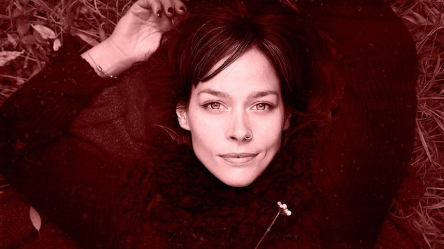 Portrait de la chanteuse Mireille Moquin couchée dans l'herbe. 